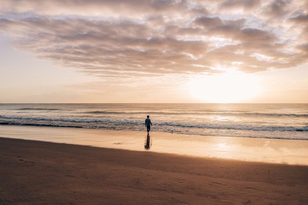 A person Healing After Betrayal alone on a beach in the sunrise